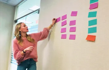Client team member organizing and sorting post-its on a large whiteboard during a kickoff